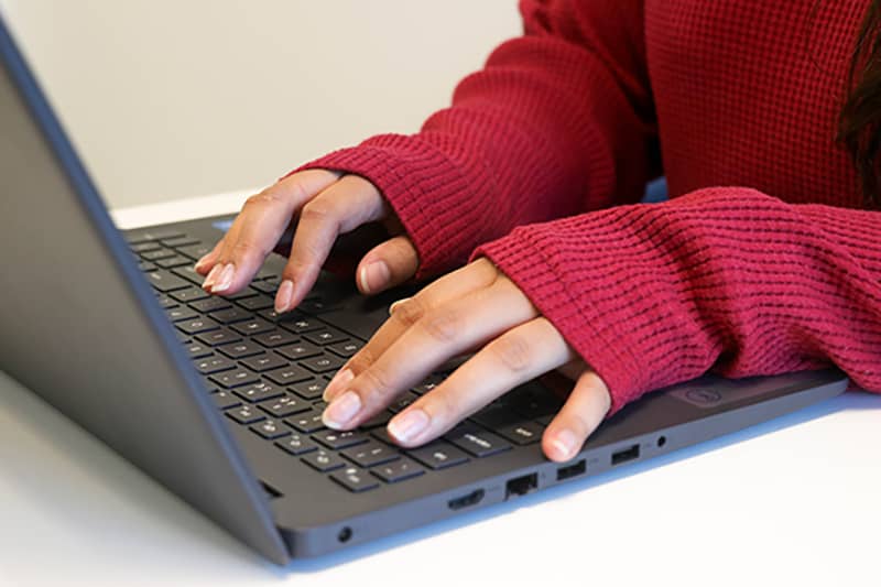 A person typing on a laptop, managing back office services.