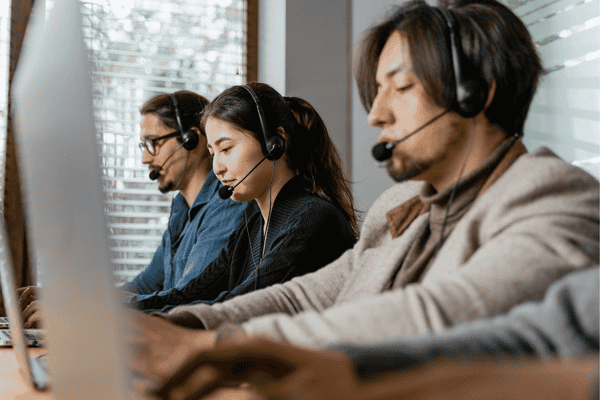 Customer support representatives wearing headsets and engaging in professional communication, showcasing the English proficiency of outsourcing teams in the Philippines.